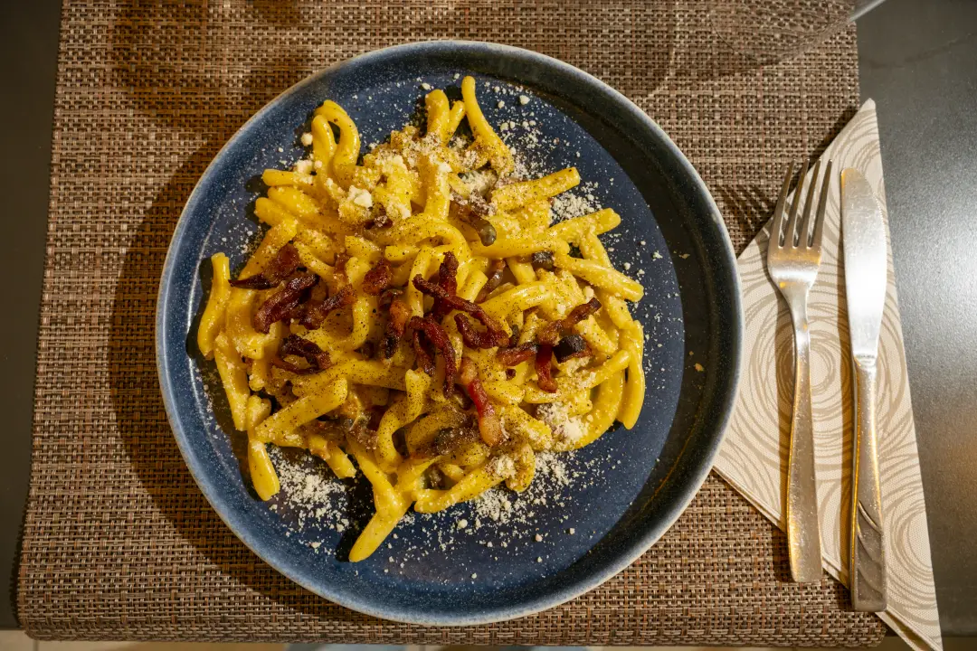 Un piatto di carbonara visto dall’alto: casarecce, guanciale e pecorino